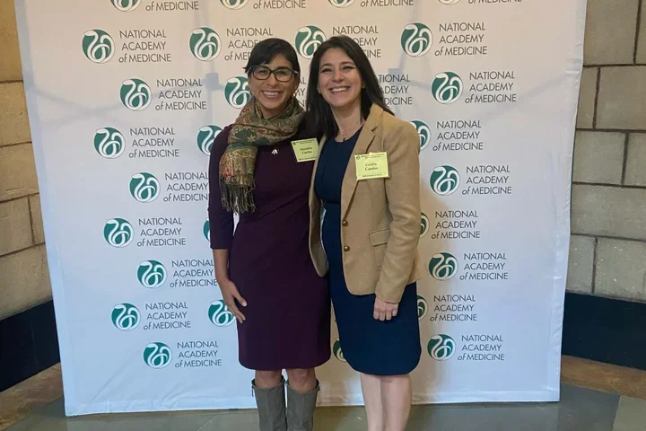 Drs. Cecilia Canales and Alejandra Casillas standing in front of a conference backdrop. 