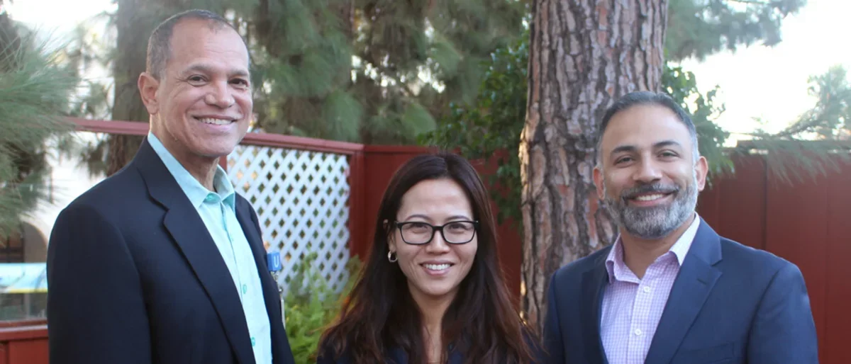 Group of three (two male and one female) scientists standing in front of tree at professional retreat
