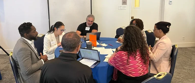 People sitting around a table at the RCMAR CHIME June 2024 Scientific Retreat - Writing Workshop
