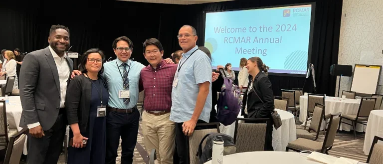 Group of scientists gathered in front of conference presentation.