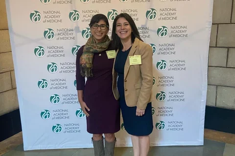 Drs. Cecilia Canales and Alejandra Casillas standing in front of a conference backdrop. 