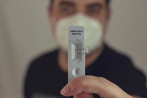 A man holds up a rapid COVID test showing a negative result.