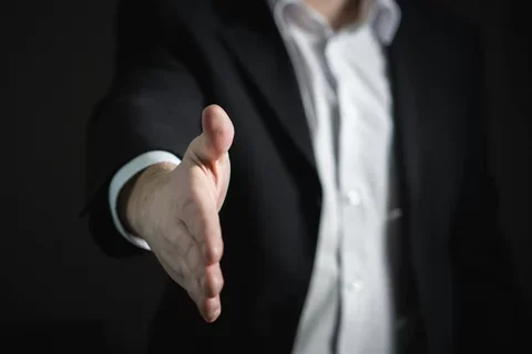 A hand is extended for a handshake.