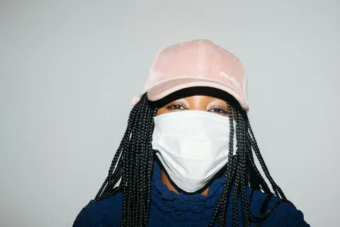 A woman in a pink baseball hat wears a face mask.