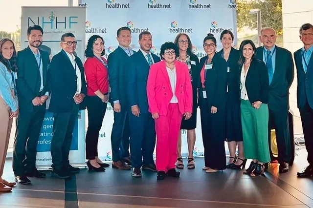 Group of Latino leadership fellows gathered in front of conference platform.
