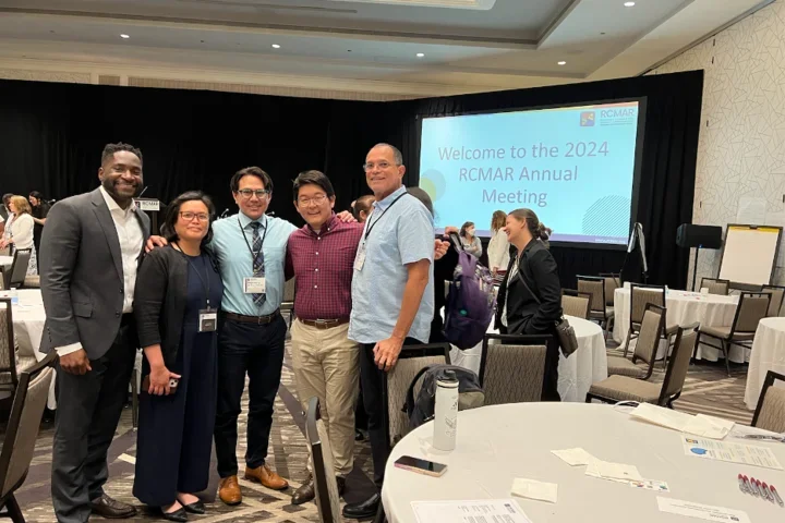 Group of scientists gathered in front of conference presentation.