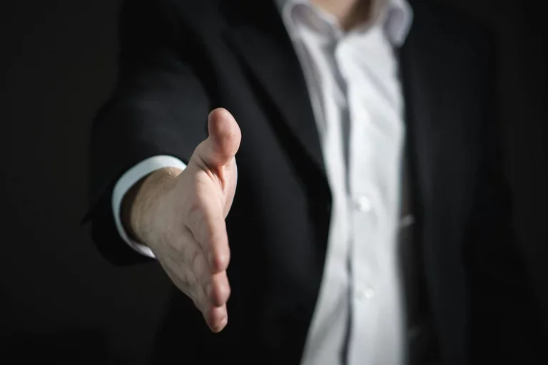 A hand is extended for a handshake. 