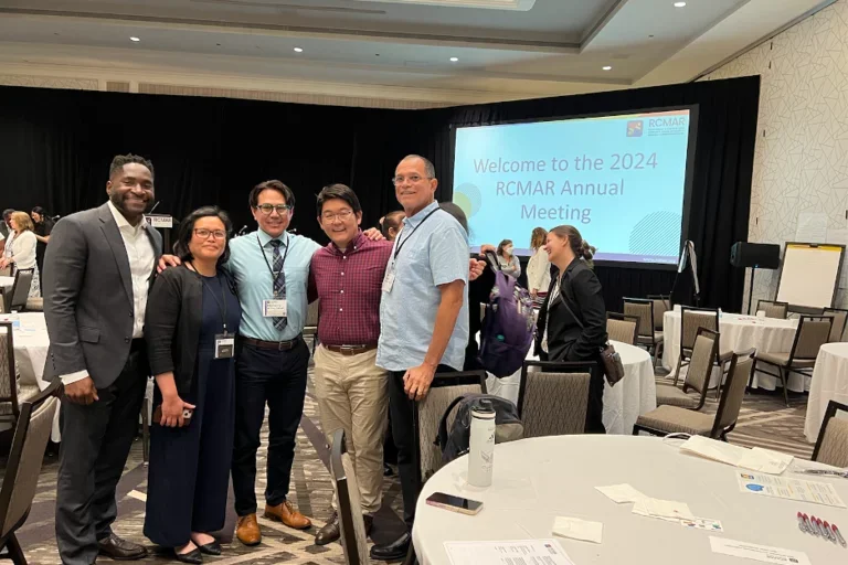 Group of scientists gathered in front of conference presentation.