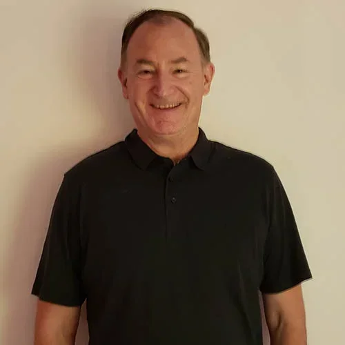 Headshot of Dr. Ron Hays with black collar shirt and beigh background.