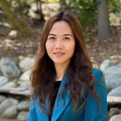 Yeonsu Song is pictured with a teal jacket and woods and rocks in the background