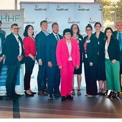 Group of Latino leadership fellows gathered in front of conference platform.