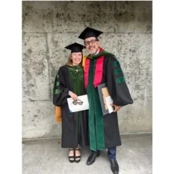 Gerardo Moreno and Carol Mangione holding awards while in cap and gown.