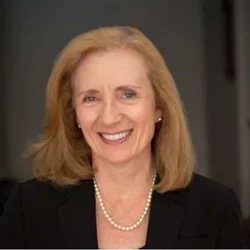 Carol Mangione is pictured here.  She is smiling and has blonde hair wearing a black jacket