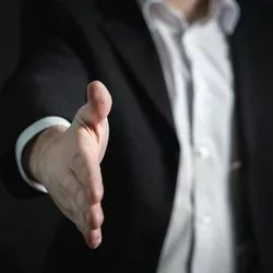 A hand is extended for a handshake. 