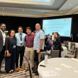 Group of scientists gathered in front of conference presentation.