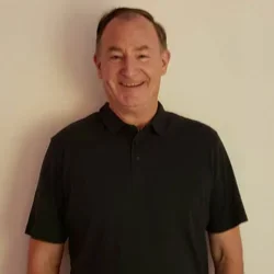 Headshot of Dr. Ron Hays with black collar shirt and beigh background.